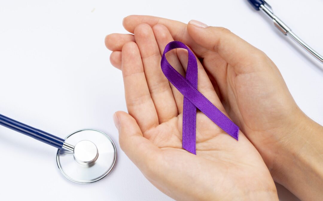 main tenant un ruban violet représentant le cancer